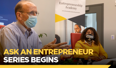Text: Ask an Entrepreneur Series Begins man speaking wearing a mask. seated next to him, a woman wearing a mask and a gold shirt. 