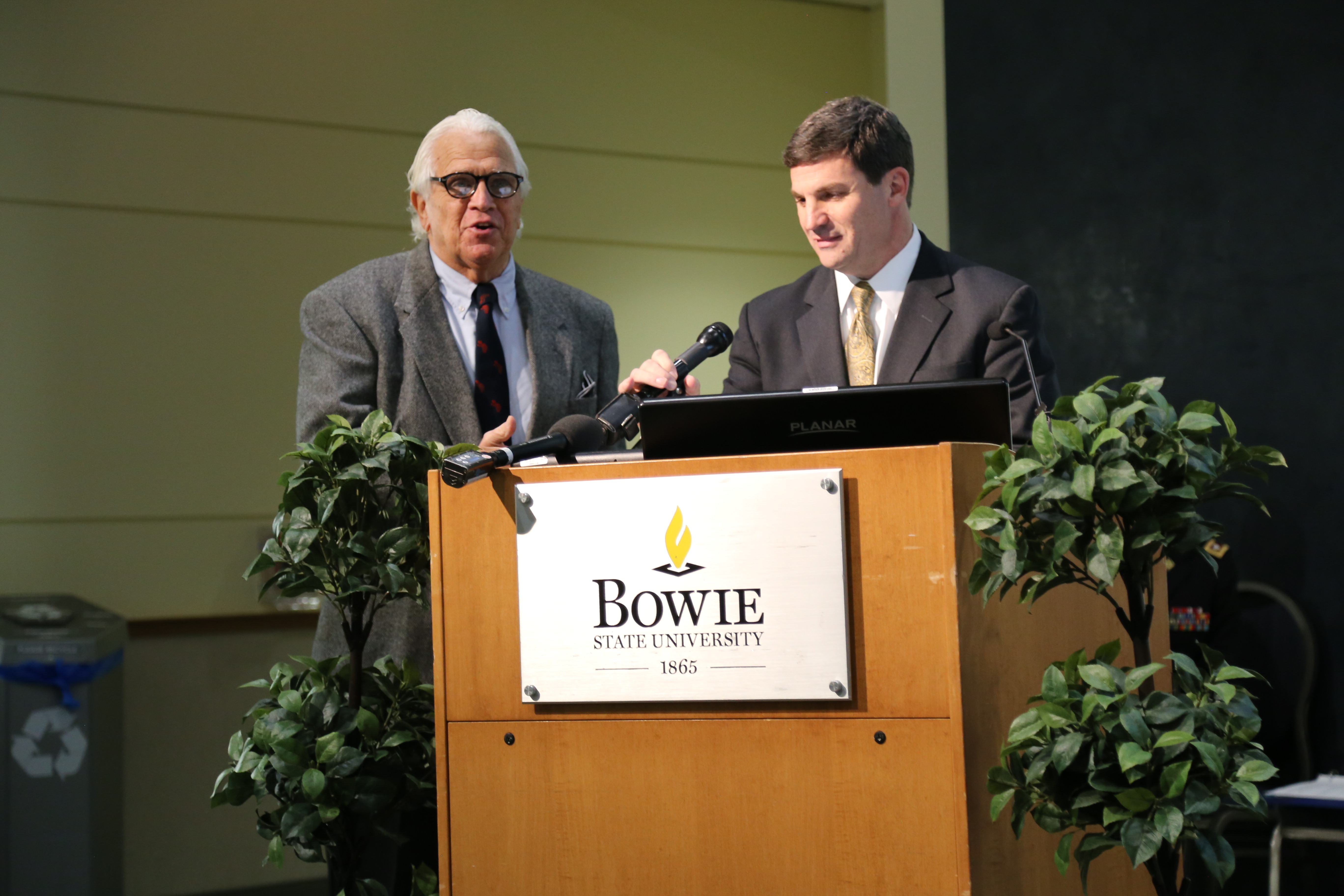 Senators Mike Miller and Douglas Peters stand at a BSU podium