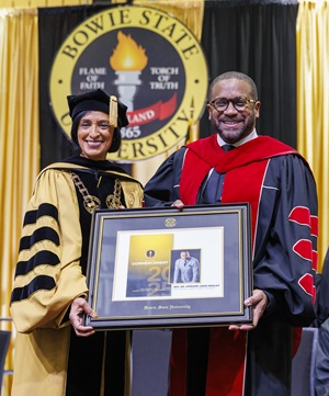  Dr. Aminta Breaux presents a gift to Rev. Dr. Howard-John Wesley at Bowie State University's 2025 Winter Commencement